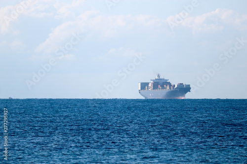 Distant view in haze of a large cargo container ship in the Mediterranean sea near Livorno, Italy