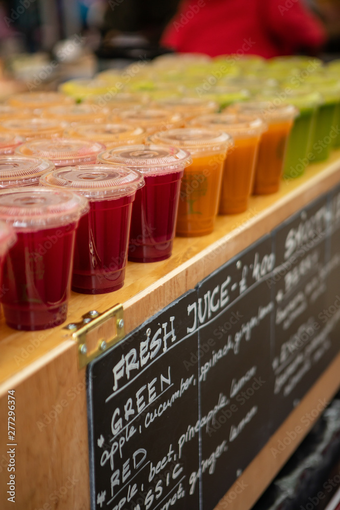 Obraz premium close up of plastic cups in a row filled with fresh juice at Stockbridge weekly market.