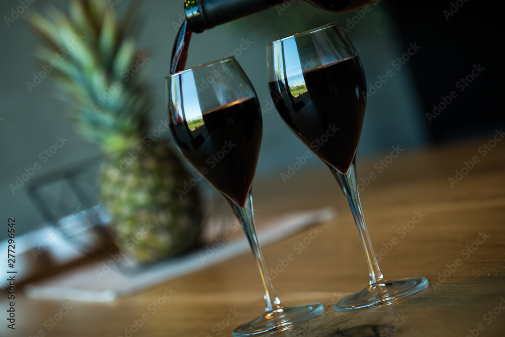 Pouring red wine on a wooden oak table Pouring red wine on a wooden oak table