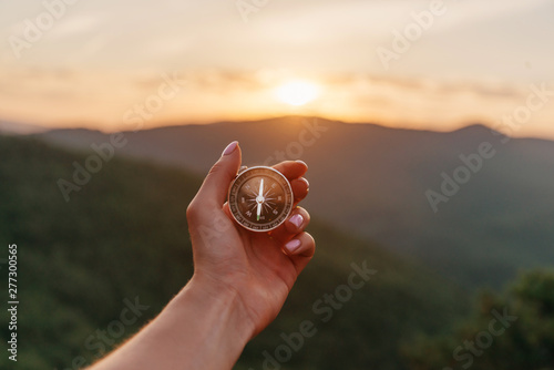 Female hand with compass in summer mountains at sunrise, pov. photo