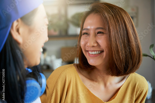 Face of happy beautiful young Asian teenage girl talking to her friend