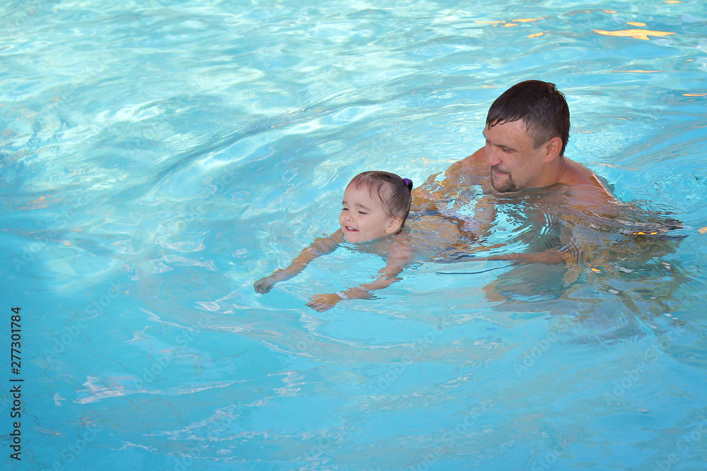 a man with a child swimming in the pool. Dad with daughter in the water