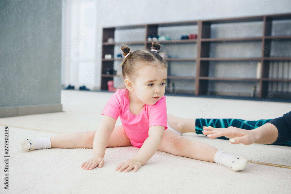 Naklejka premium little girl engaged in recreational gymnastics. sports exercises and stretching: athletics