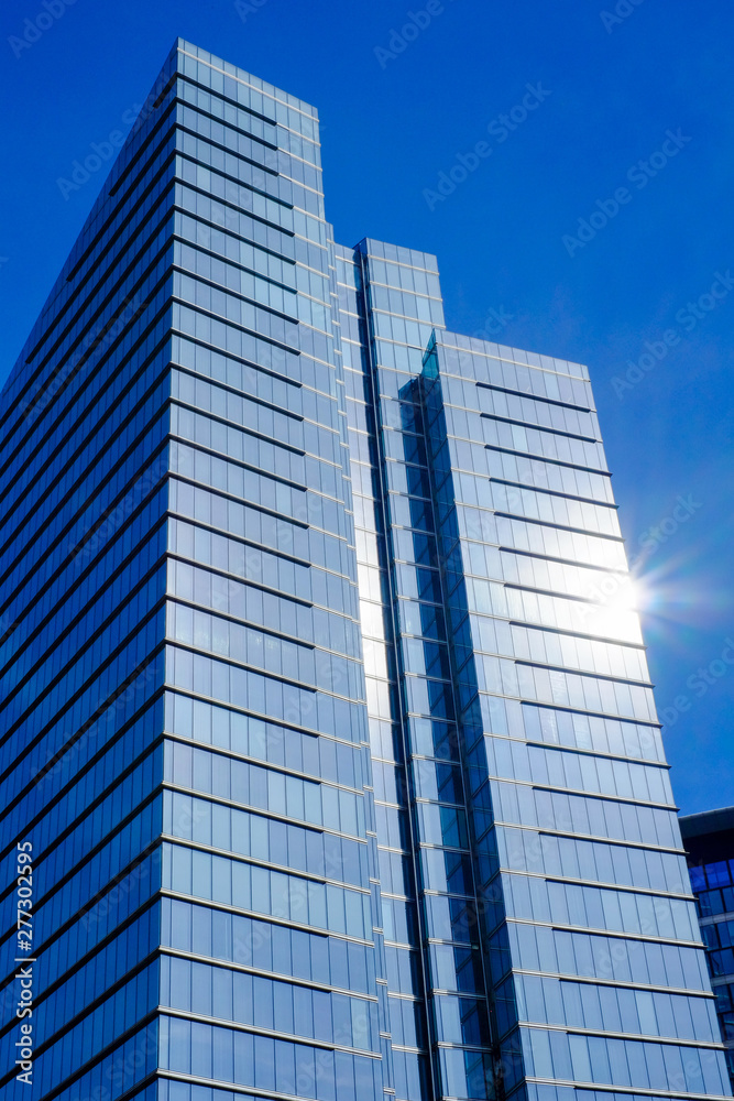 Low angle view of modern business buildings in city against blue clear sky Low angle view of modern business buildings in city against blue clear sky