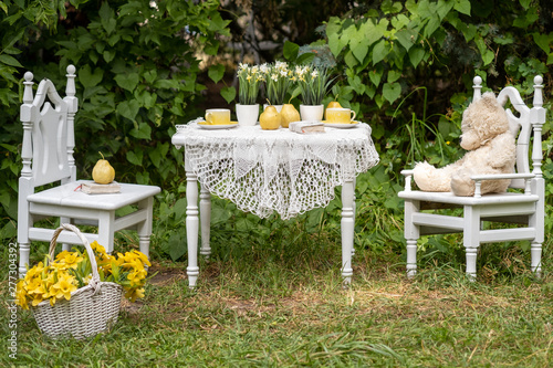 Fototapeta Naklejka Na Ścianę i Meble -  Vintage garden with white tea table and wooden chairs