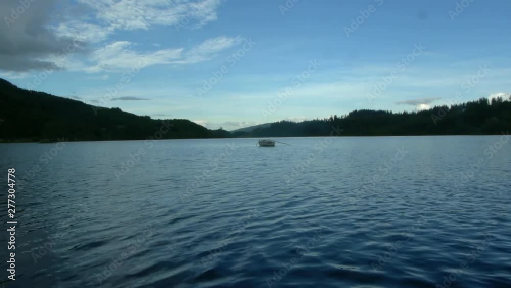 Empty wooden rowing boat on Scottish lake on summers day Empty wooden rowing boat on Scottish lake on summers day