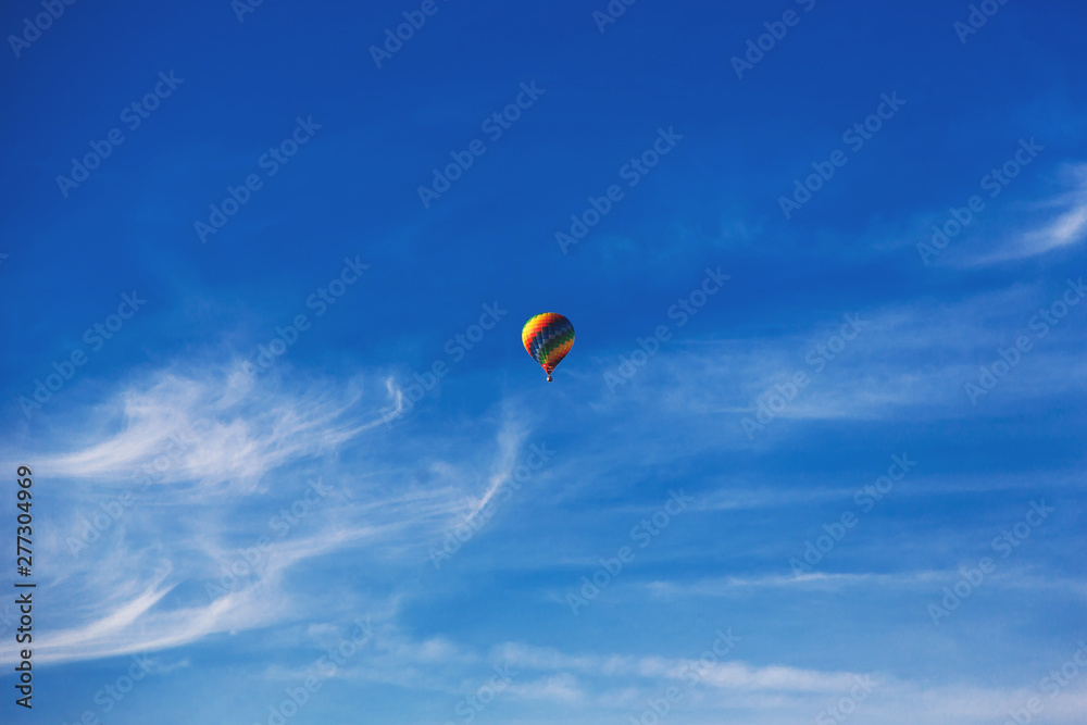 Fototapeta premium Balloon flying through the blue sky among the clouds. Freedom, adventure, loneliness.