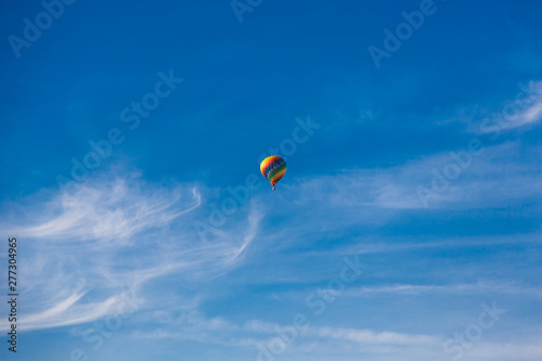 Balloon flying through the blue sky among the clouds. Freedom, adventure, loneliness.