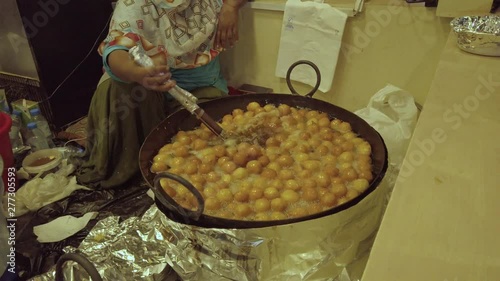 Slowmotion of Cooking Lakma or  Luqma, Sweet Arabic Dessert. Mixing Pastries With Ladle in Honey Syrup photo