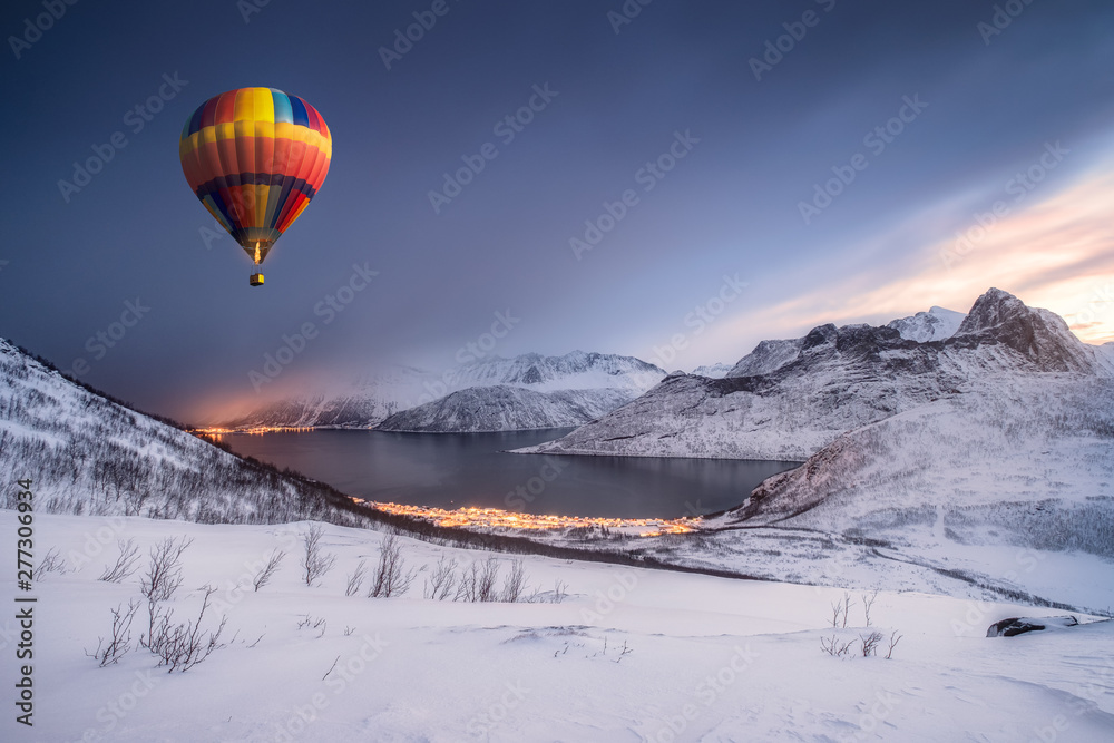 Hot air balloon flying on snow hill with fordgard town in winter