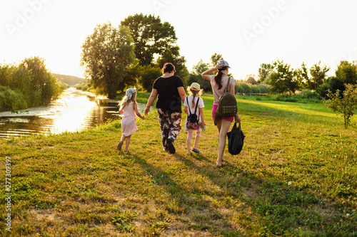 Happy family going for a walk on the bank of the river in the sunrise.