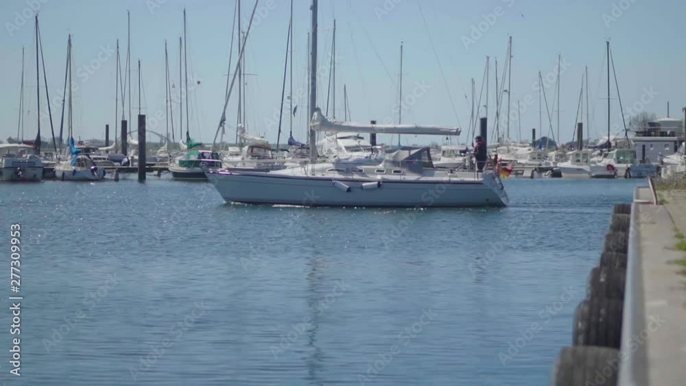 Sailing vessel leaving harbour by motor on a sunny day Sailing vessel leaving harbour by motor on a sunny day