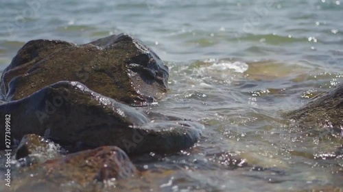 Slow Motion, waves splashing over rocks and wash around them on a sunny day
