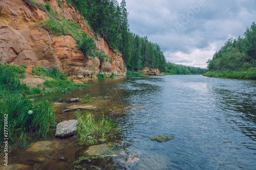 City Cesis  Latvia Republic. Red rocks and river Gauja. Nature  and green trees in summer. Jul 5. 2019 Travel photo.