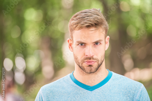 Charming confidence. Blond man. Man with unshaved mustache and beard hair with stylish haircut. Handsome man in casual tshirt on blurred natural background. Caucasian man on summer day