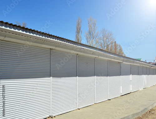 Closed non-working tents in mall along road to sea beach in resort village. Early spring, deserted, off season. Bright sun illuminates metal blinds