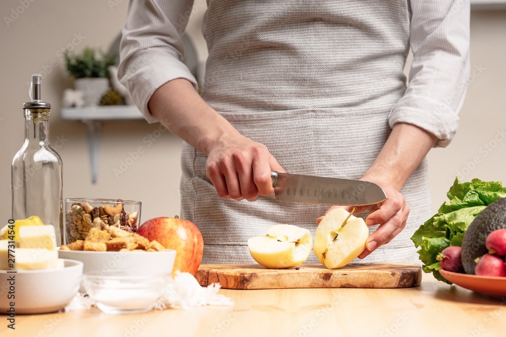 The chef prepares a vegetarian salad with the hand of a chef in the home kitchen. Light background with text area for restaurant menu design. The concept of healthy eating, cooking salad