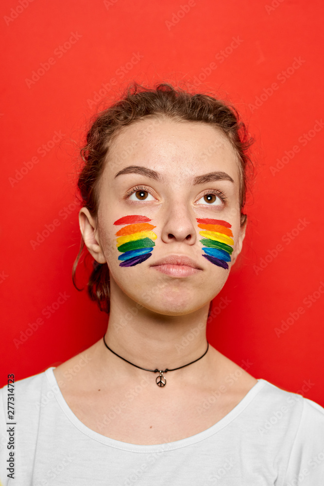 Girl with pride flag painted on her cheeks smiling