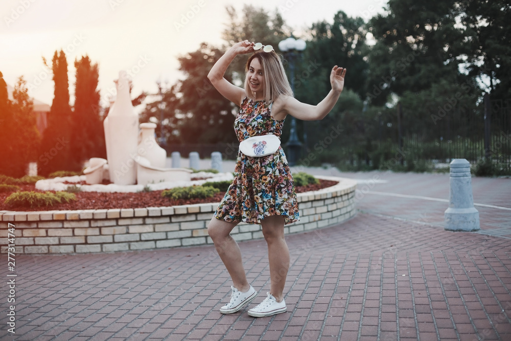 Young happy woman with beige belt cotton bag on it standing at the street with smile and sunglasses in summer dress. Young happy woman with beige belt cotton bag on it standing at the street with smile and sunglasses in summer dress.