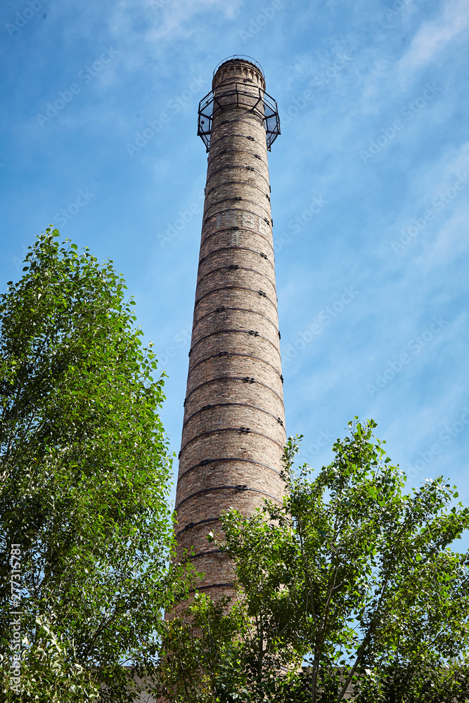 Brick chimney and trees. Industry, ecology.