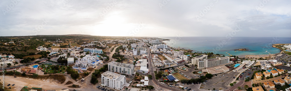 Aerial panoramic drone shot of Protaras city at sunset in a cloudy day