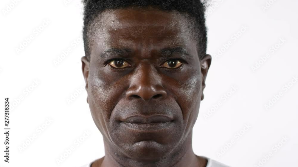 Close up shot of serious middle aged African man tilting up his head and looking at camera while posing against white background Close up shot of serious middle aged African man tilting up his head and looking at camera while posing against white background