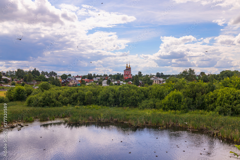 Rural  landscape with houses, church, pond and summer greenery, Suzdal, Russia