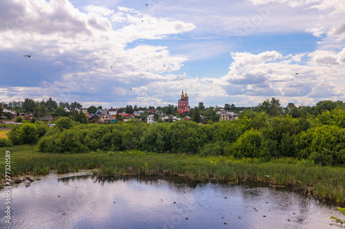 Rural landscape with houses, church, pond and summer greenery, Suzdal, Russia