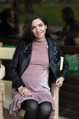 pregnant girl sitting in a cafe. Attractive pregnant brunette sitting on a sofa on a cafe terrace