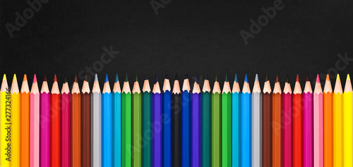Row of colorful wooden pencils on black background with copy space, back to school concept