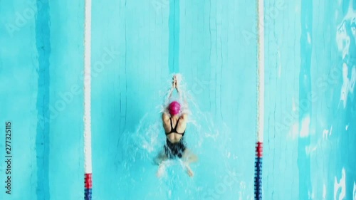 From above view of female professional athlete training and swimming in breaststroke style in clear blue water of pool line 