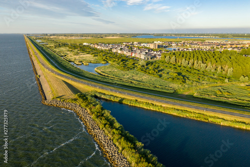 A dike in The Netherlands seen from the sky. A lake on the left, suburban area on the right. photo