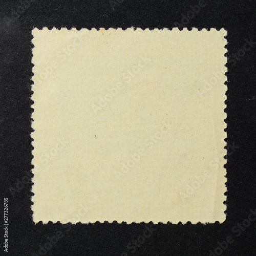 Blank vintage square postage stamp on black background. Mockup with perforations for your picture text or design.