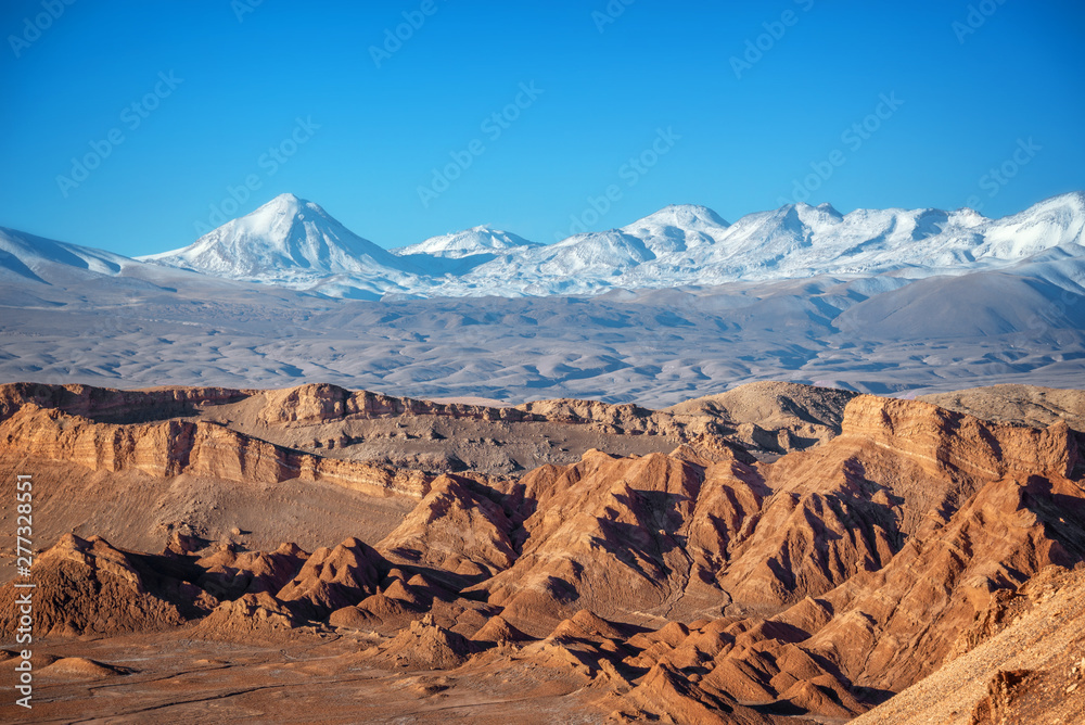 Panorama of Moon Valley in Atacama desert, snowy Andes mountain range in the background, Chile