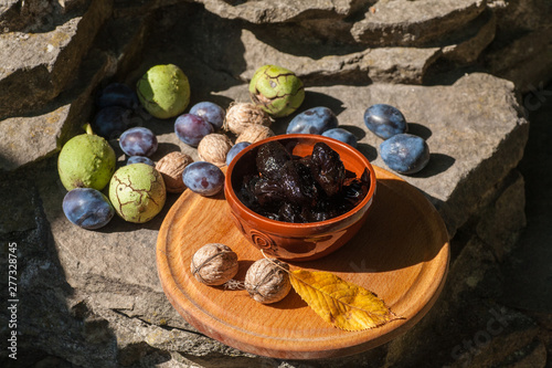 Fresh and dried prunes whit walnuts in bowl. Natural food. Outdur composition. Close up. photo