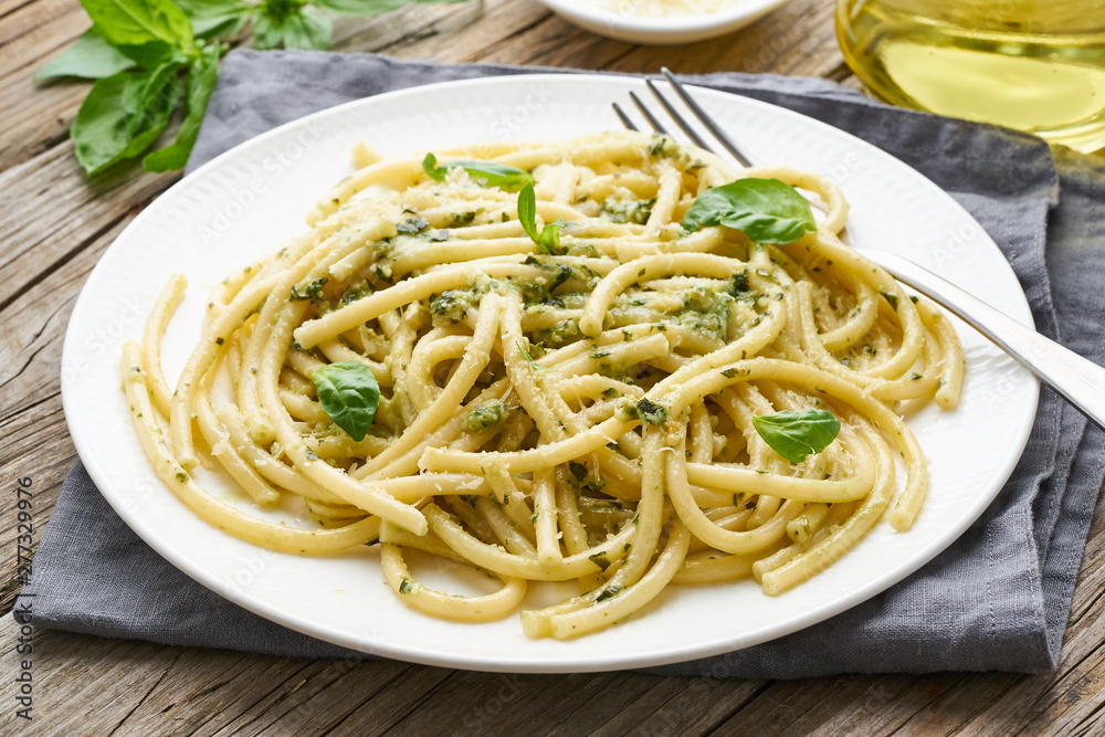 Pesto spaghetti pasta with basil, garlic, pine nuts, olive oil. Rustic table, close up