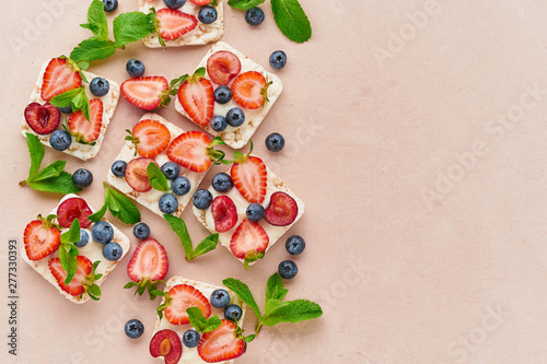 Rise crispbread with berries and fruits colorful concept on terracotta background copy space top view