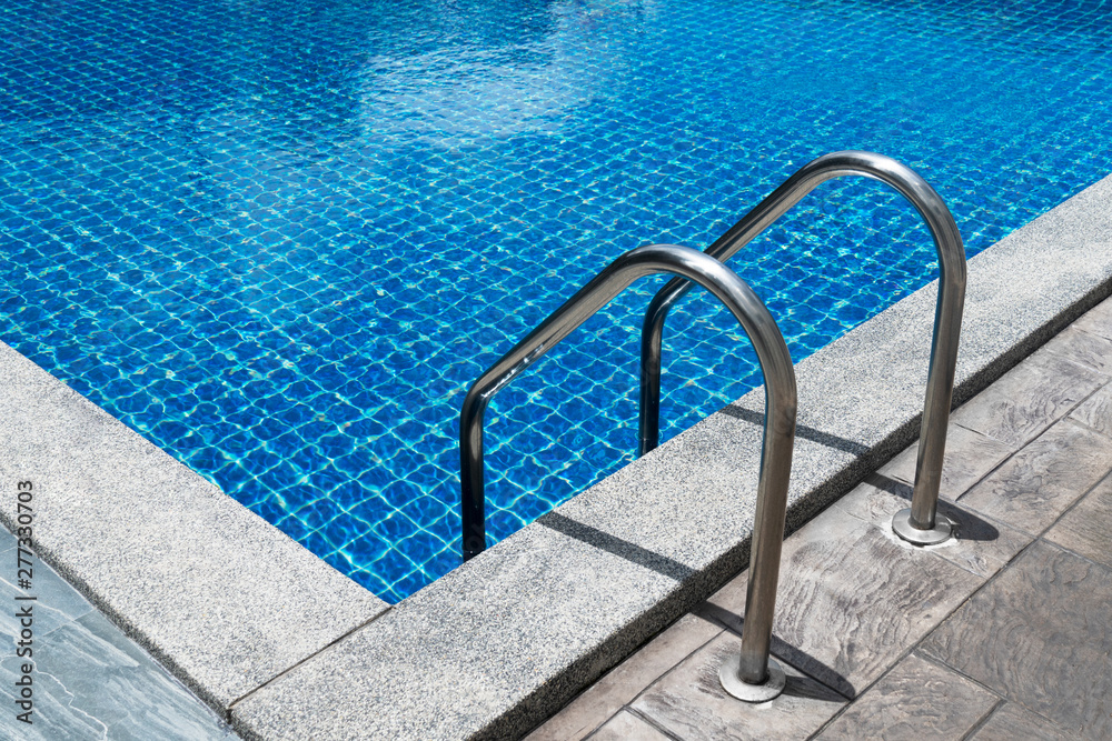 metal stainless steel ladder in summer blue swimming pool water for vacation travel refreshment background