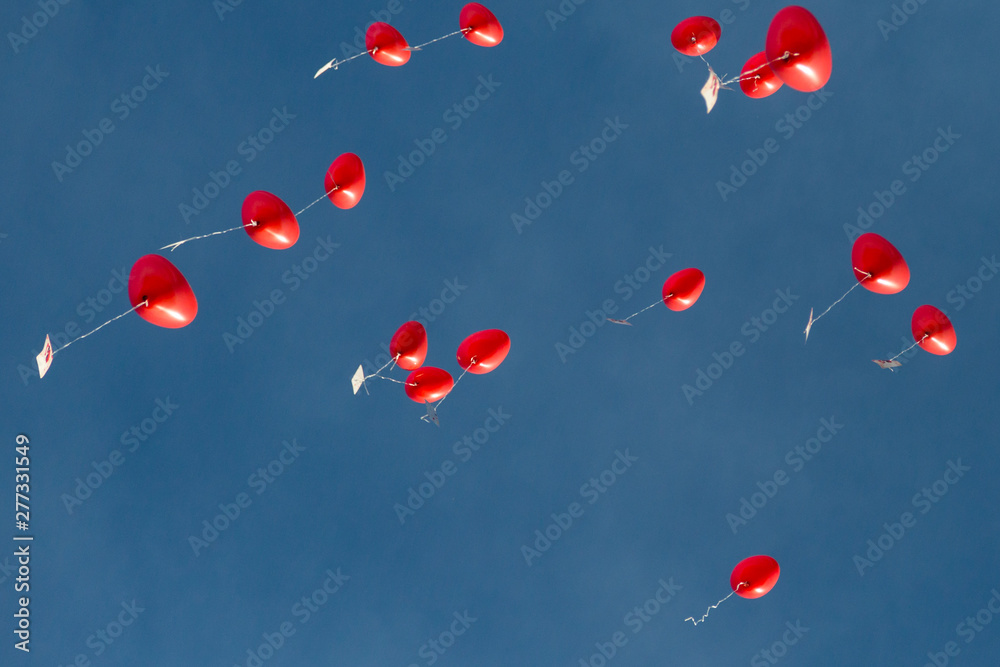 several red heart-shaped balloons in flight, blue sky several red heart-shaped balloons in flight, blue sky