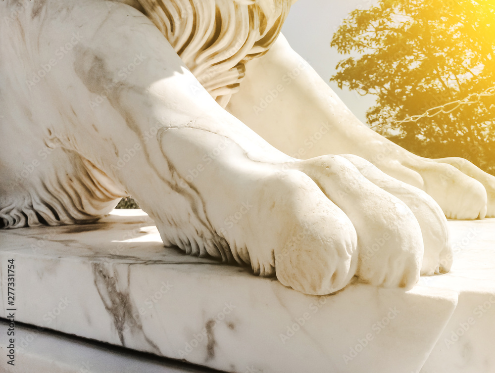 white sculpture close-up of marble powerful paw of a lion on a pedestal in the sunlight white sculpture close-up of marble powerful paw of a lion on a pedestal in the sunlight