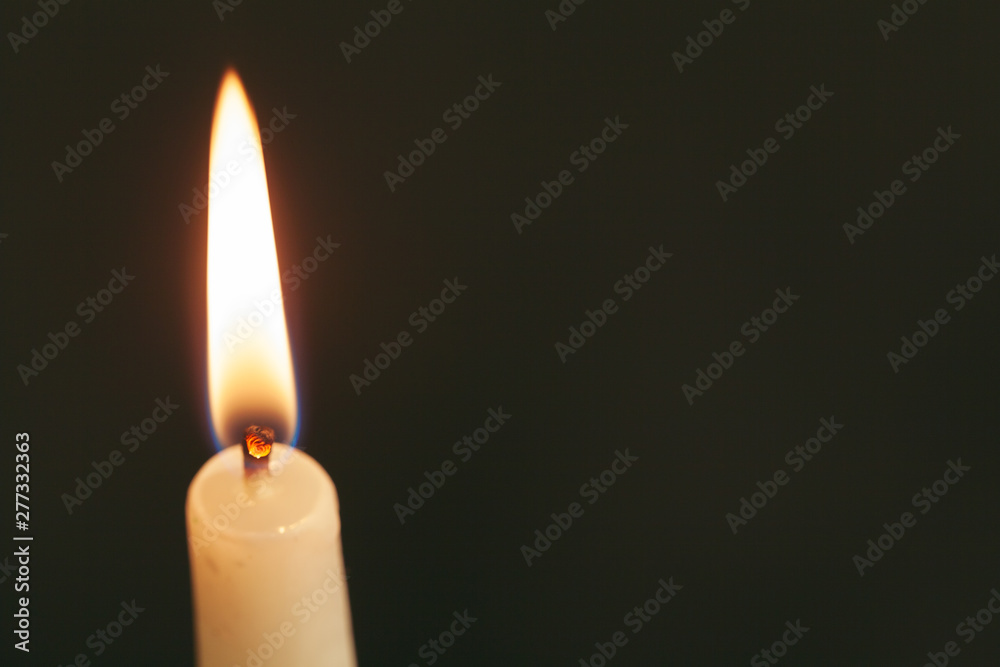 A single burning candle isolated with black background A single burning candle isolated with black background
