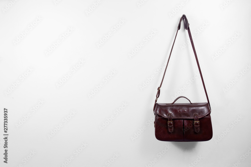 Vintage brown leather bag hung on a white wall