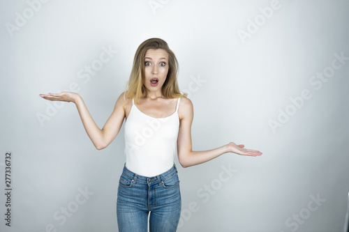 young beautiful woman surprised showing scales sign isolated white background