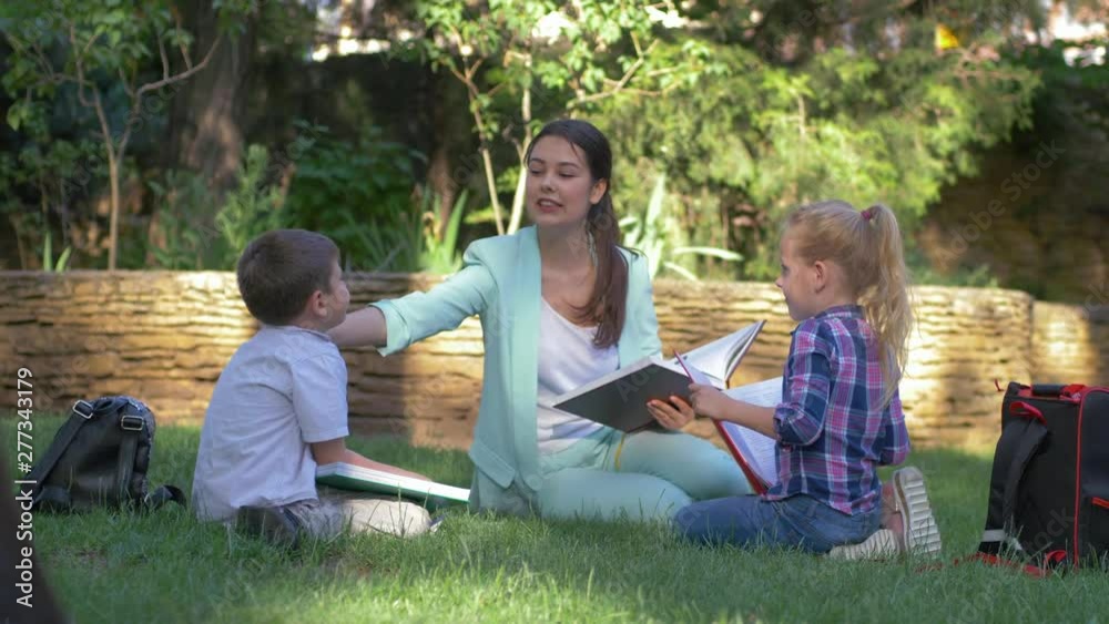 outdoor lesson, happy classmate learners boy and girl with educator female read books and chat during teaching on open air outdoor lesson, happy classmate learners boy and girl with educator female read books and chat during teaching on open air