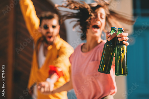 Canvas Print Young couple dancing on the street and holding two bottles of beer