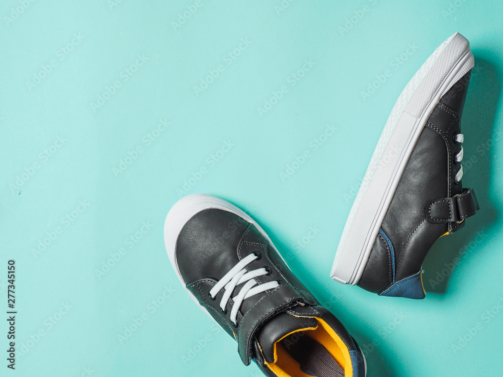 pair of new kids or adult sneakers on blue background, top view. Flat lay gray and yellow or mustard color sneakers shoes on colorful bright blue background with copy space for text or design - obrazy, fototapety, plakaty 