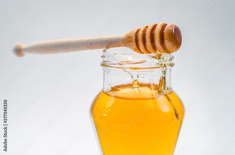 Close up of wooden honey spoon on class jar full of honey Close up of wooden honey spoon on class jar full of honey