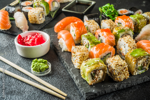Assorted sushi set on stone or concrete background. Japanese classic sushi, sushi nigiri. rolls, soy sauce, ginger, chopsticks. Top view. copy space