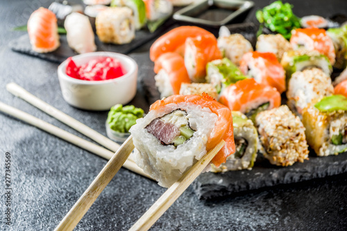 Assorted sushi set on stone or concrete background. Japanese classic sushi, sushi nigiri. rolls, soy sauce, ginger, chopsticks. Top view. copy space