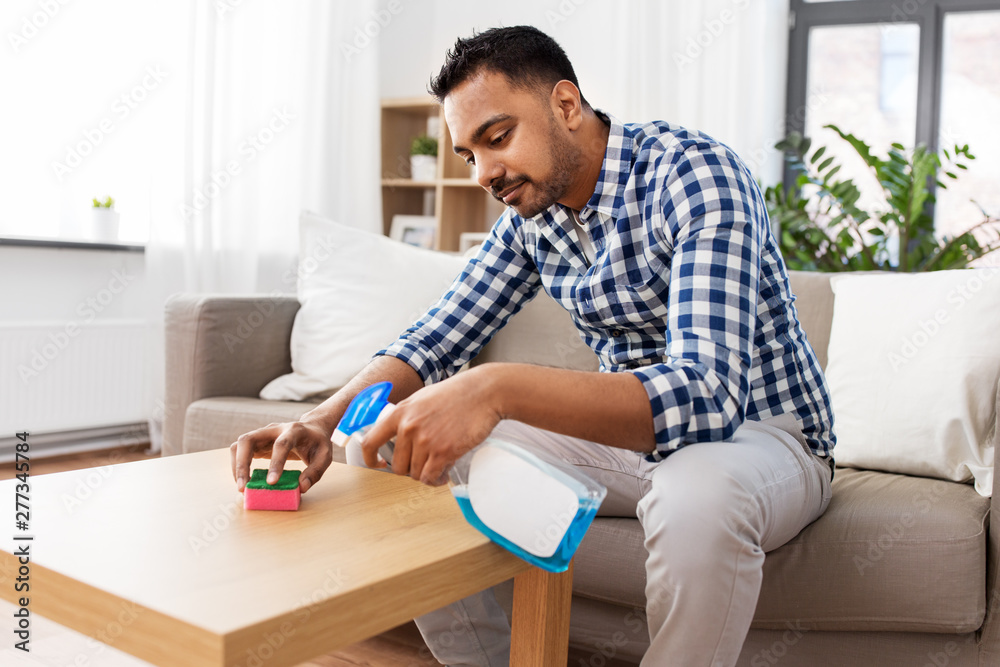 household and people concept - indian man cleaning table with detergent at home